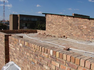 Roof waterproofing with pipes on brick roof surface in progress.
