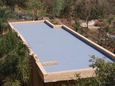 Flat concrete roof waterproofing with protective coating in progress.