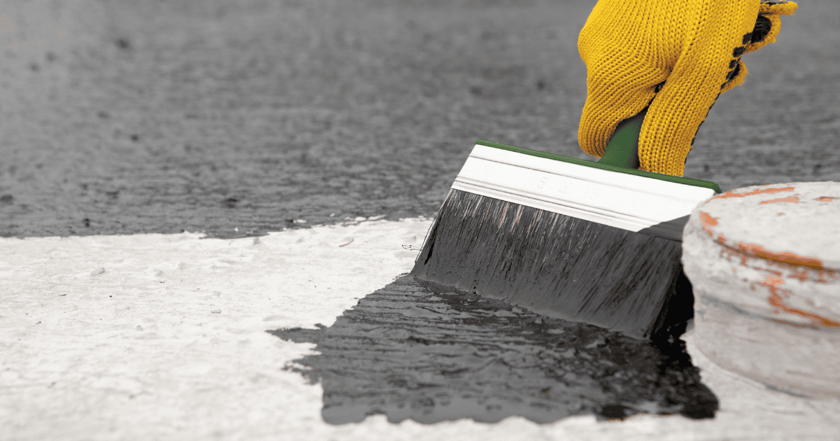 Applying waterproofing membrane on a flat roof for repair and protection.