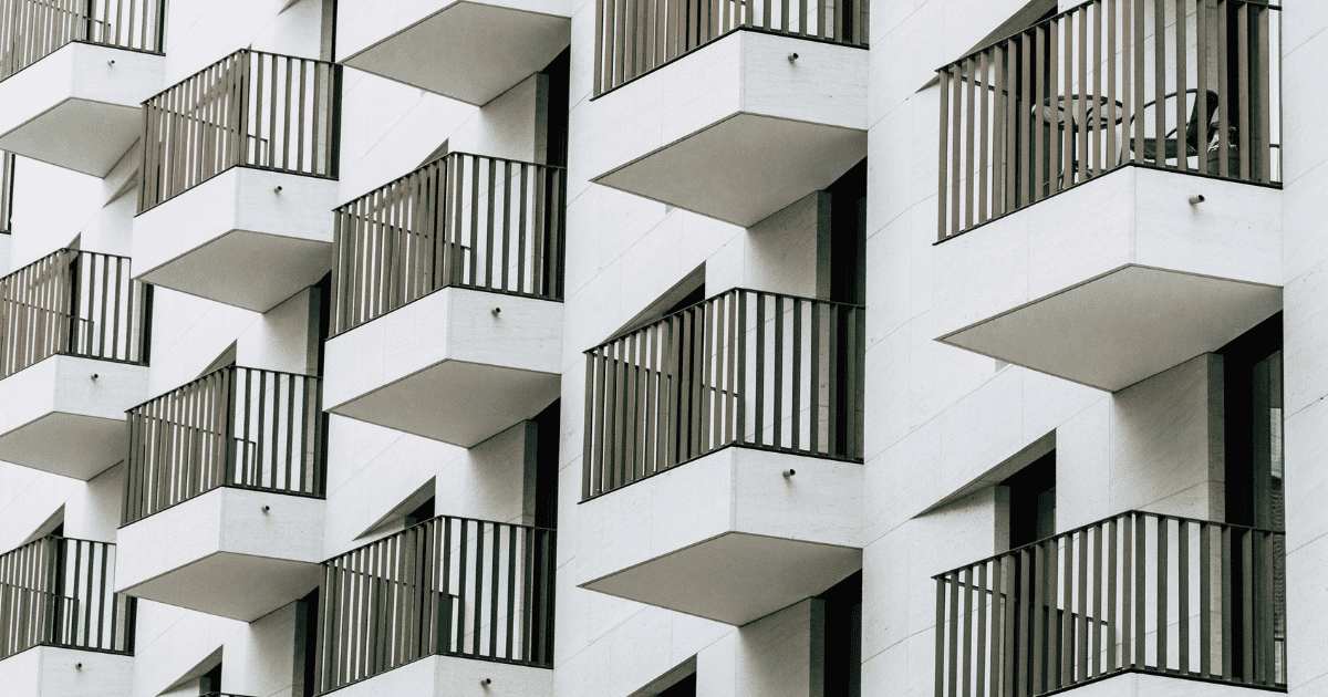 Multiple balconies with black railings on a white building facade.