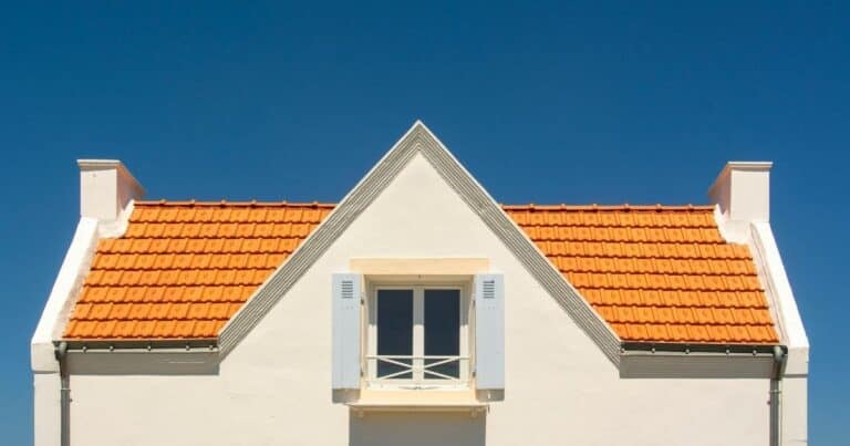 Blog House roof with orange tiles and white walls under a clear blue sky.