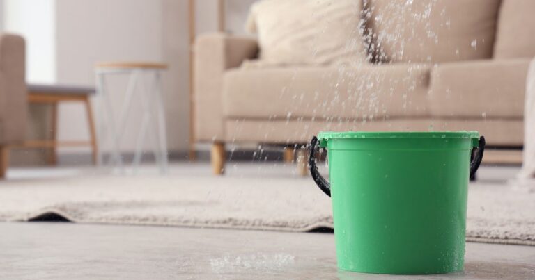 Blog Green bucket spilling water on living room floor for cleaning.
