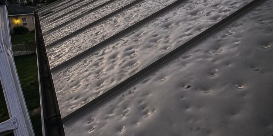 Close-up of hail damage on roof shingles from recent hailstorm.